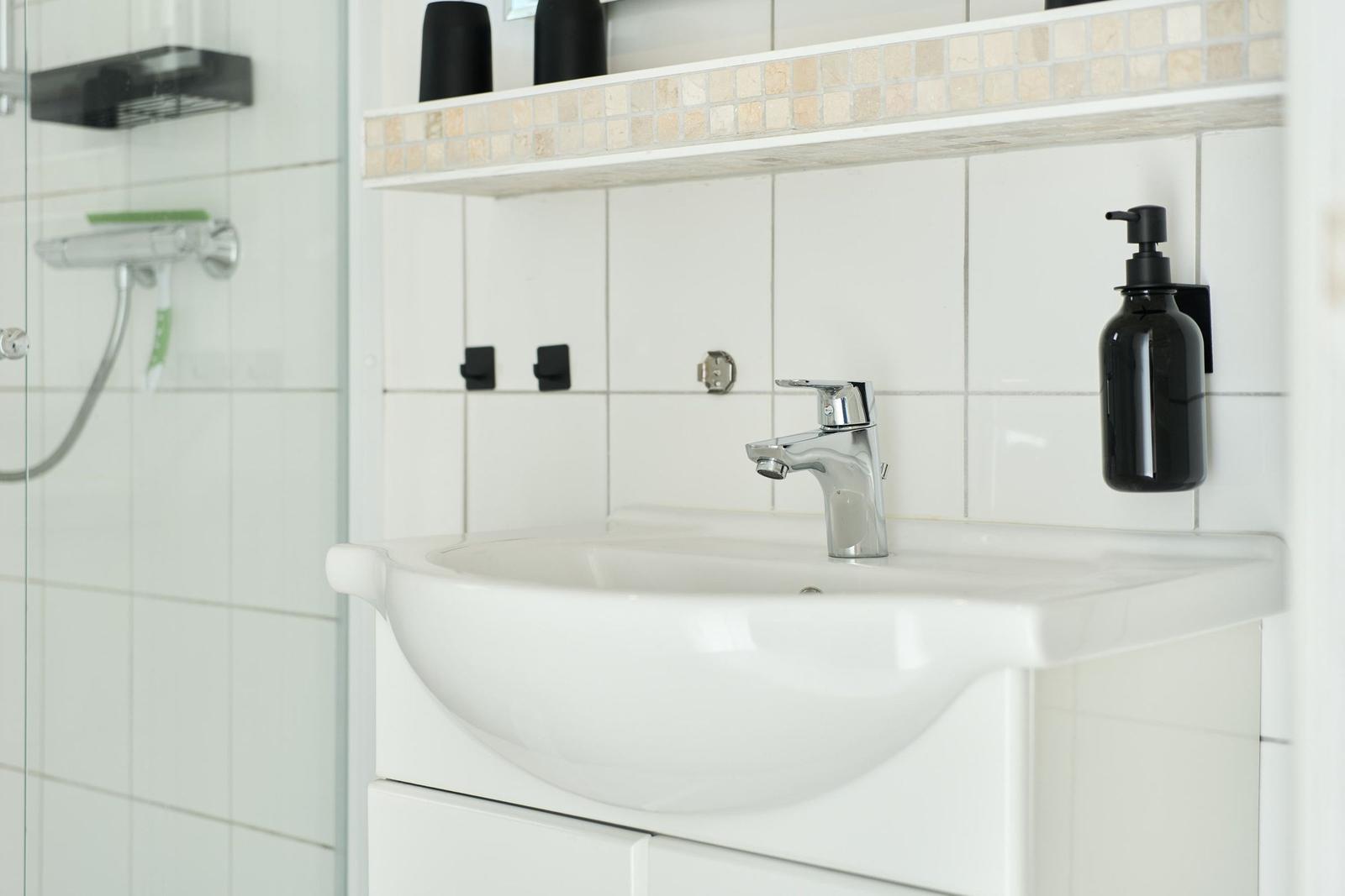 Waschbecken mit Wasserhahn und Duschabtrennung im Badezimmer