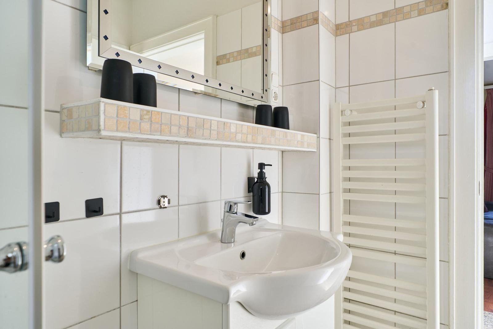 Badezimmer mit Waschbecken, Spiegel und Heizkörper an der Wand.
