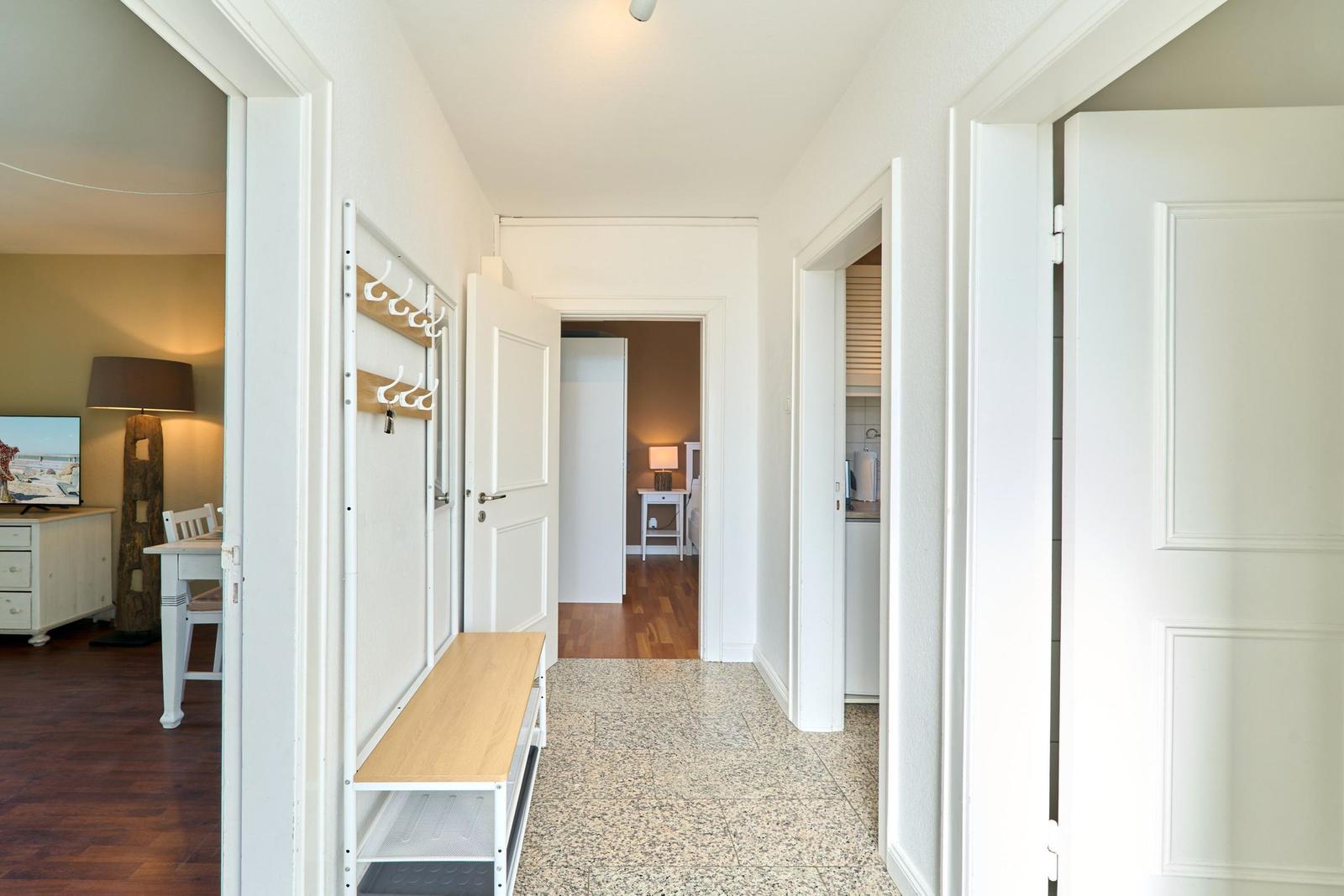 Flur mit Kleiderhaken, Sitzbank und Blick in Wohn- und Schlafzimmer.