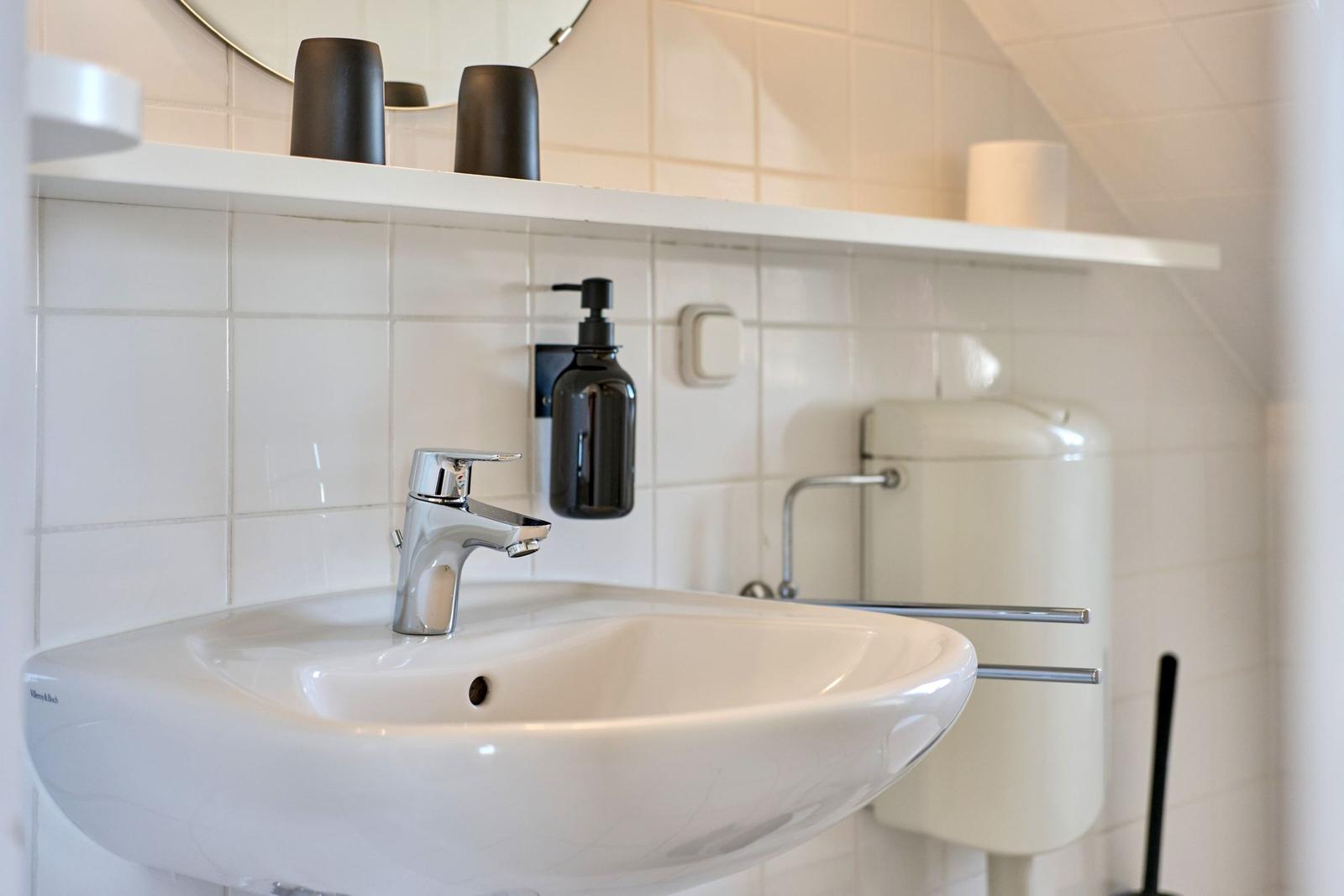 Waschbecken mit Wasserhahn und Spiegelschrank im Badezimmer.