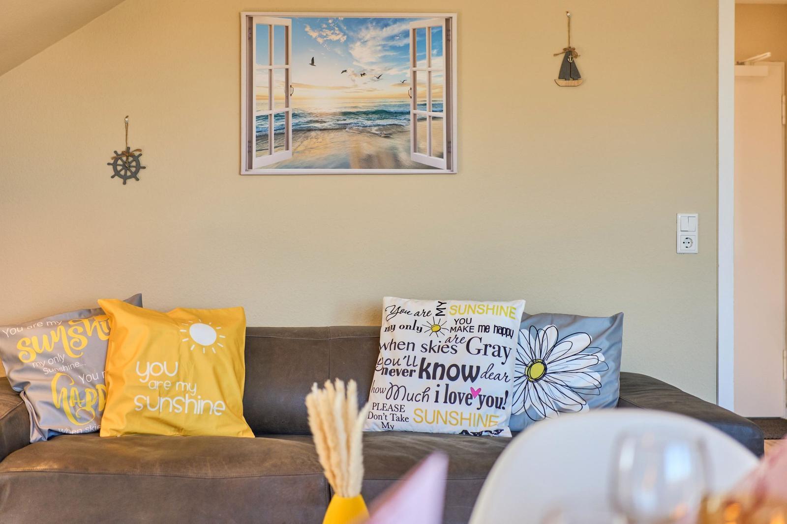Sofa mit Kissen und Wandbild mit Meerblick