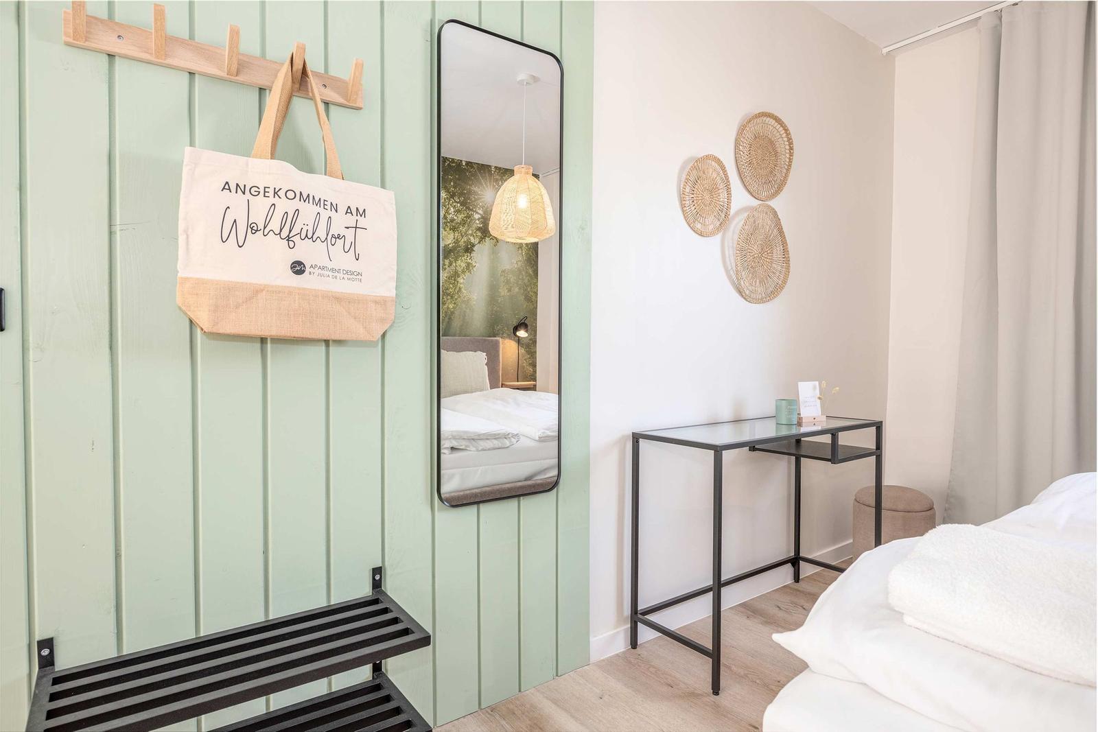 Schlafzimmer mit Spiegel, Schreibtisch und Wanddekoration.
