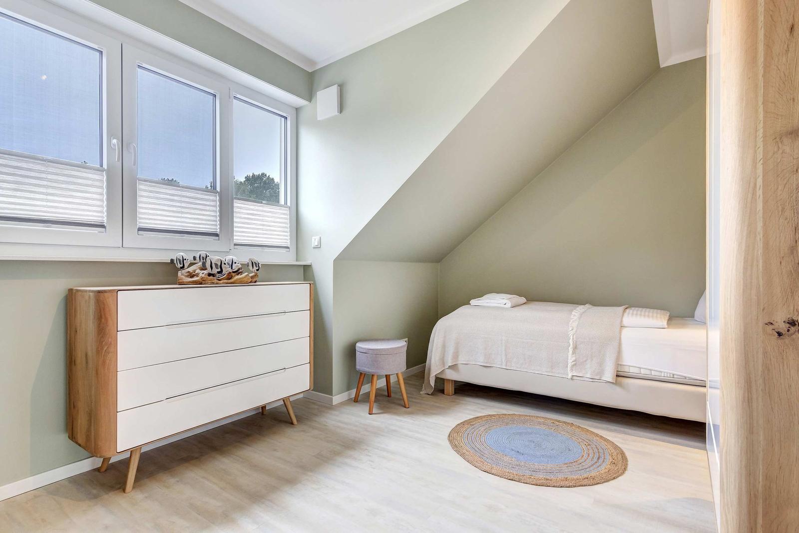 Schlafzimmer mit Dachschräge, Bett, Schrank und Fenster