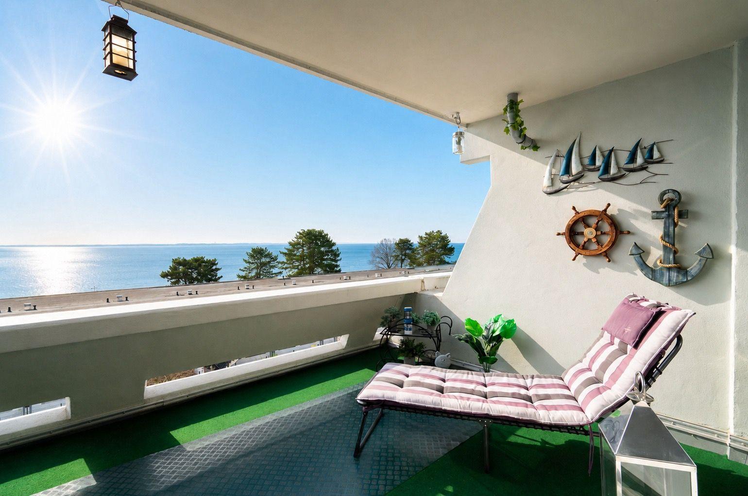 Terrasse mit Liegestuhl und Meeresblick. Wanddekoration mit Segelbooten, Ruder und Anker.