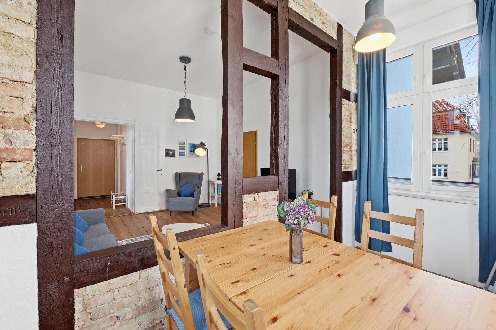 Dining room with wooden table and chairs. Passage to living area with sofa and armchair.