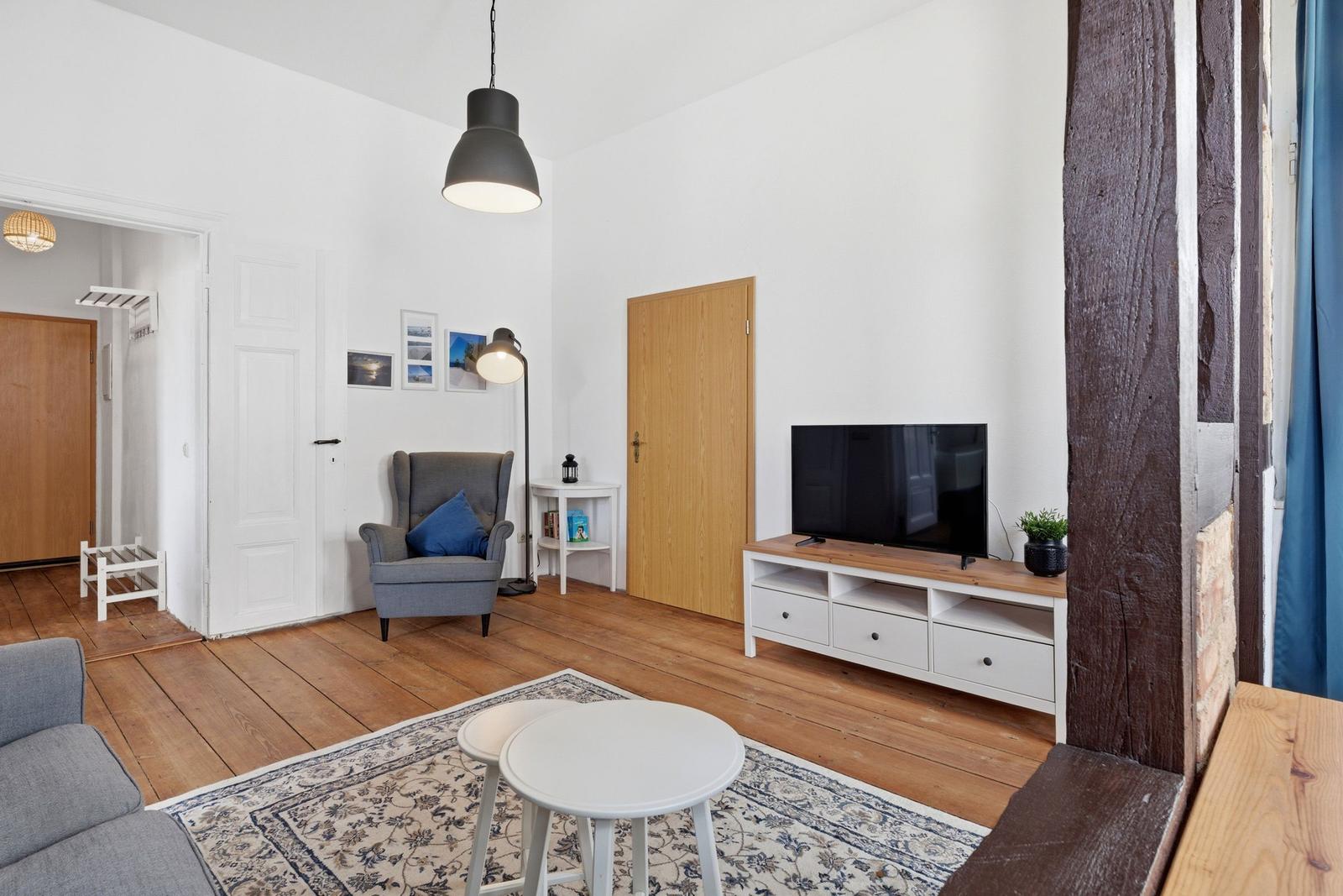 Living room with TV, armchair, and wooden floor. A room with modern furnishings.