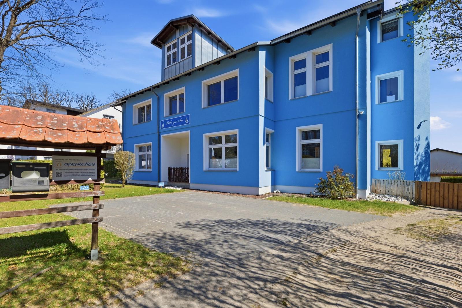 Blue-painted house with multiple windows and entrance area.