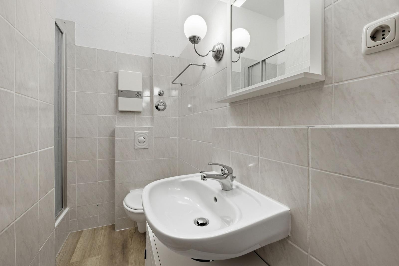 Bathroom with sink, mirror, shower, and toilet.