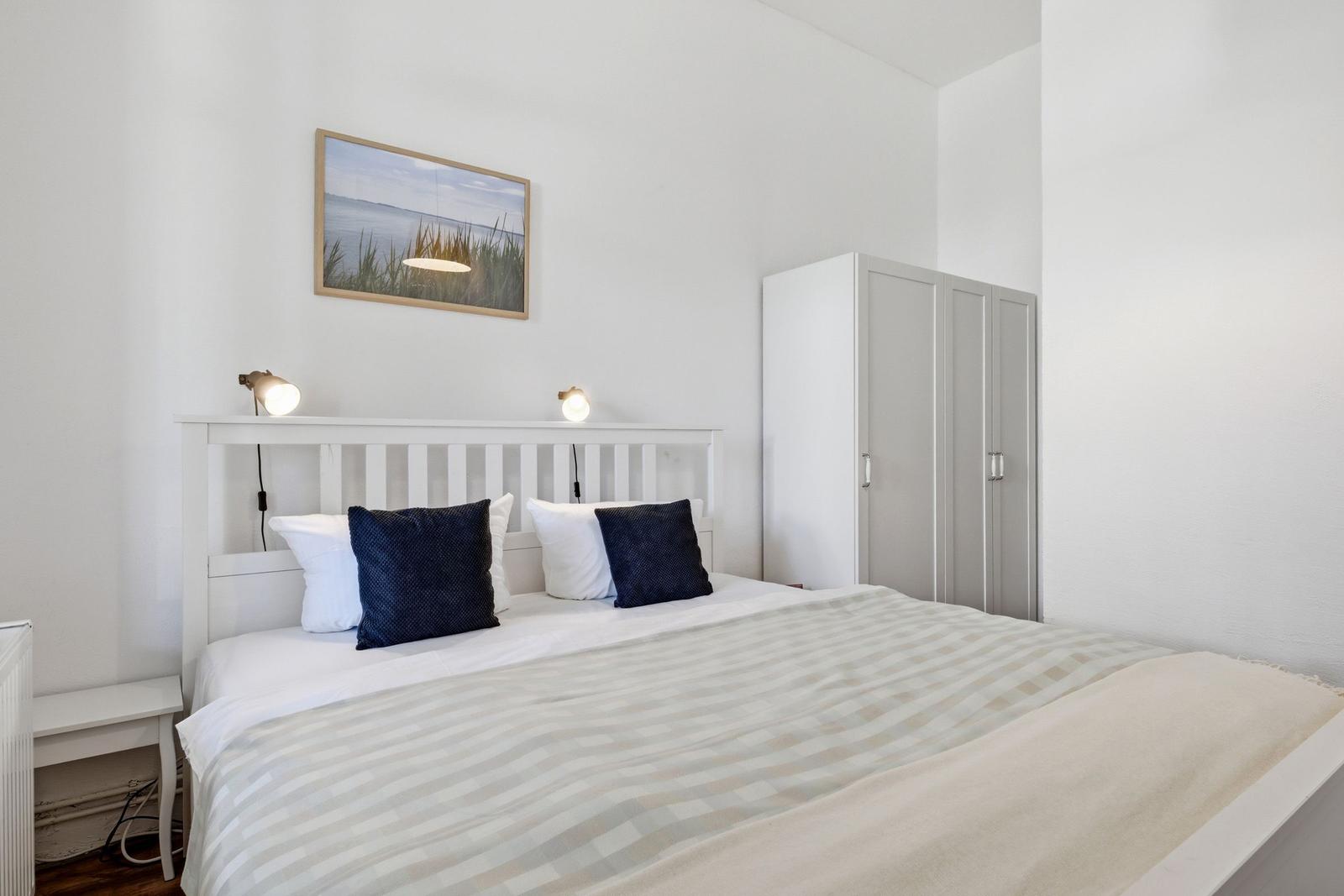 Bedroom with bed, wardrobe, and wall picture.