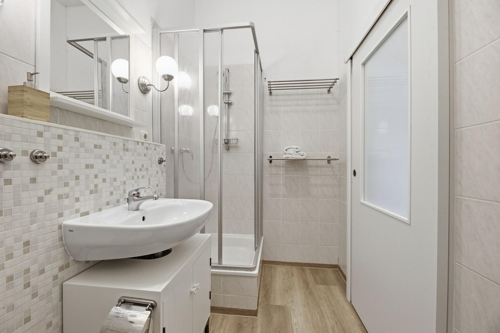 Badezimmer mit Dusche, Waschbecken und Spiegel