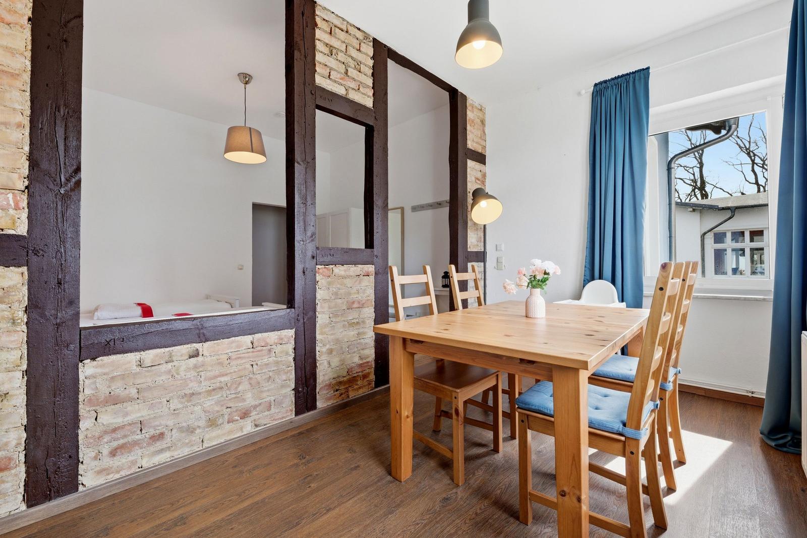 Esszimmer mit Holztisch und Stühlen, Blick in Schlafzimmer mit Holzrahmen.