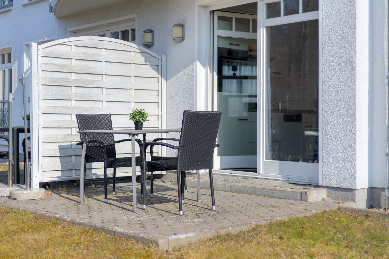 Terrasse mit Tisch und zwei Stühlen vor der Haustür.