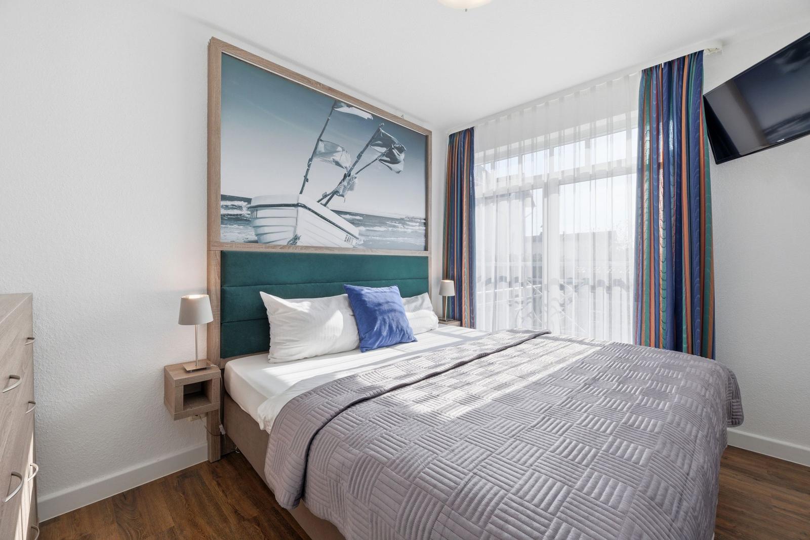 Schlafzimmer mit Bett, Wandbild und Fenster mit Vorhängen.