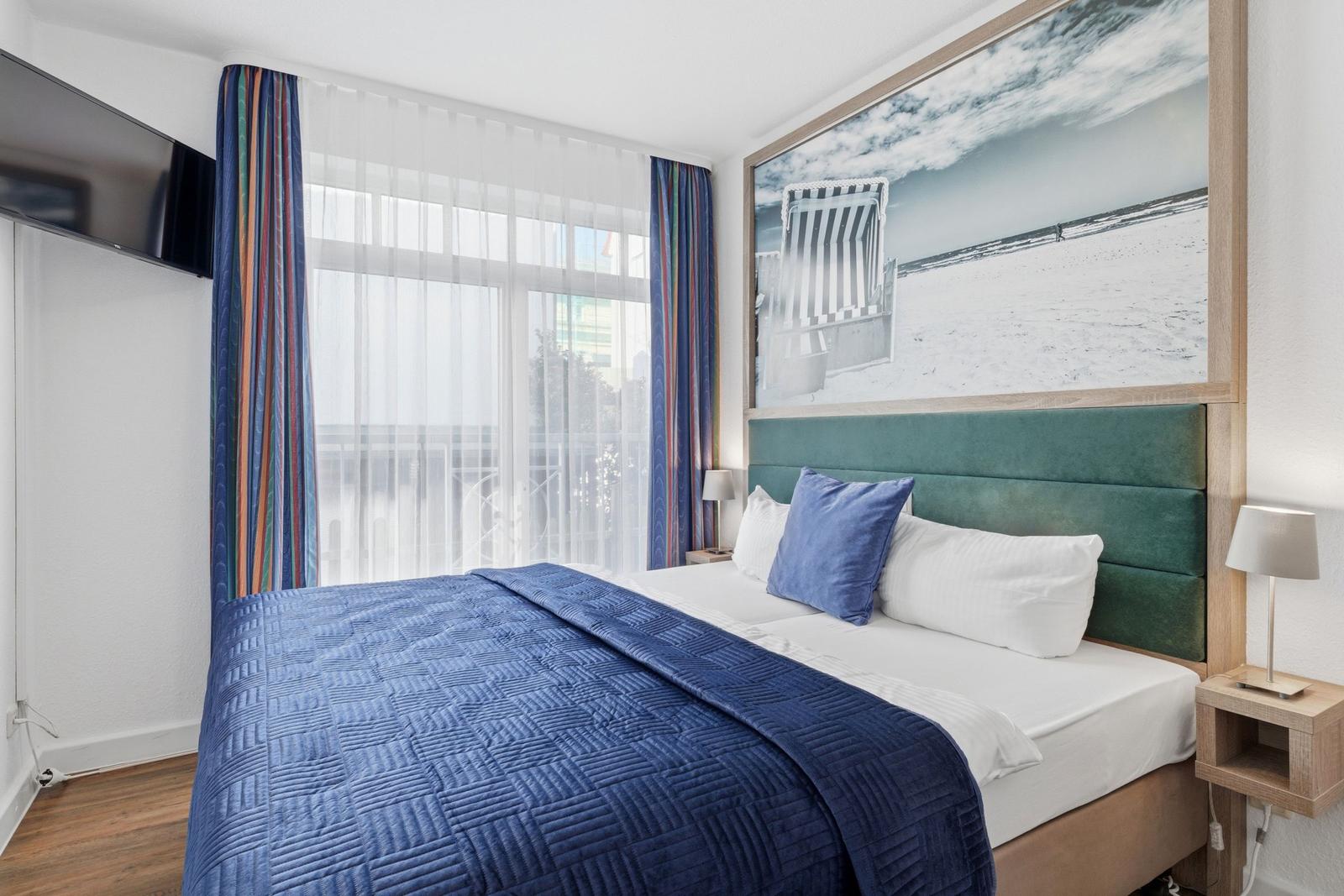 Schlafzimmer mit Bett, Fenster, TV und Wandbild