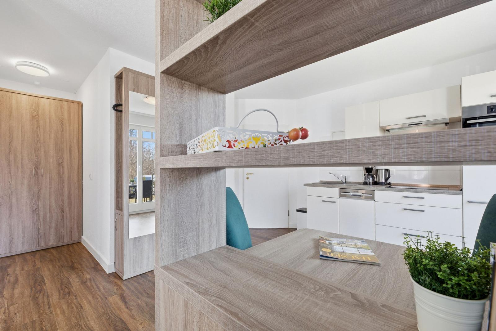 Küche mit Arbeitsplatz und Aufbewahrungsbereich. Holzoptik und weiße Schränke.