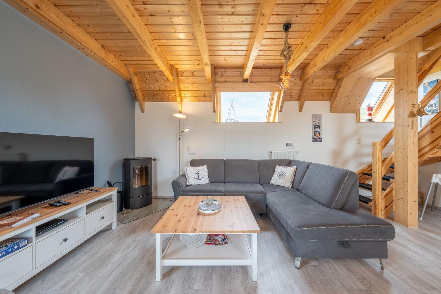Wohnzimmer mit grauem Sofa, Holzdecke und TV-Möbel