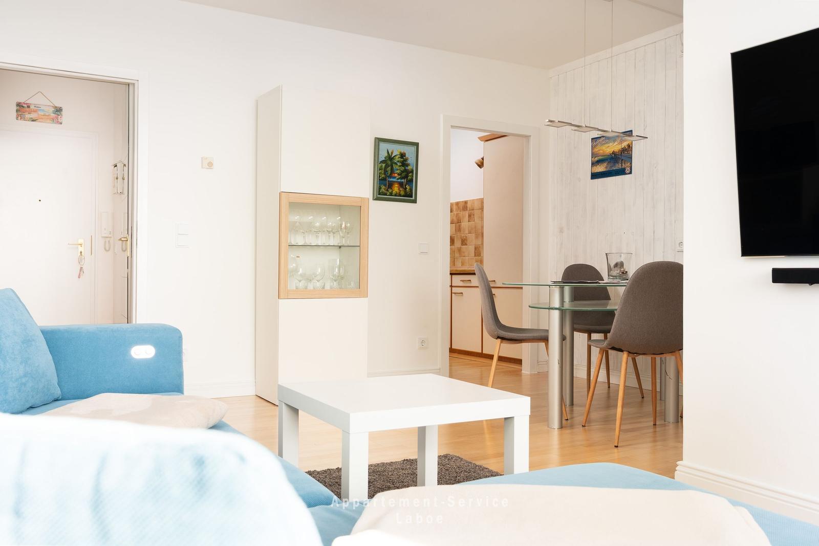 Wohnzimmer mit Sofa, Couchtisch und Blick in die Küche.