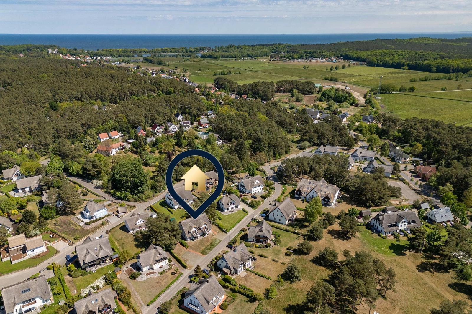 Aerial view of a residential area near the sea with forests and fields.