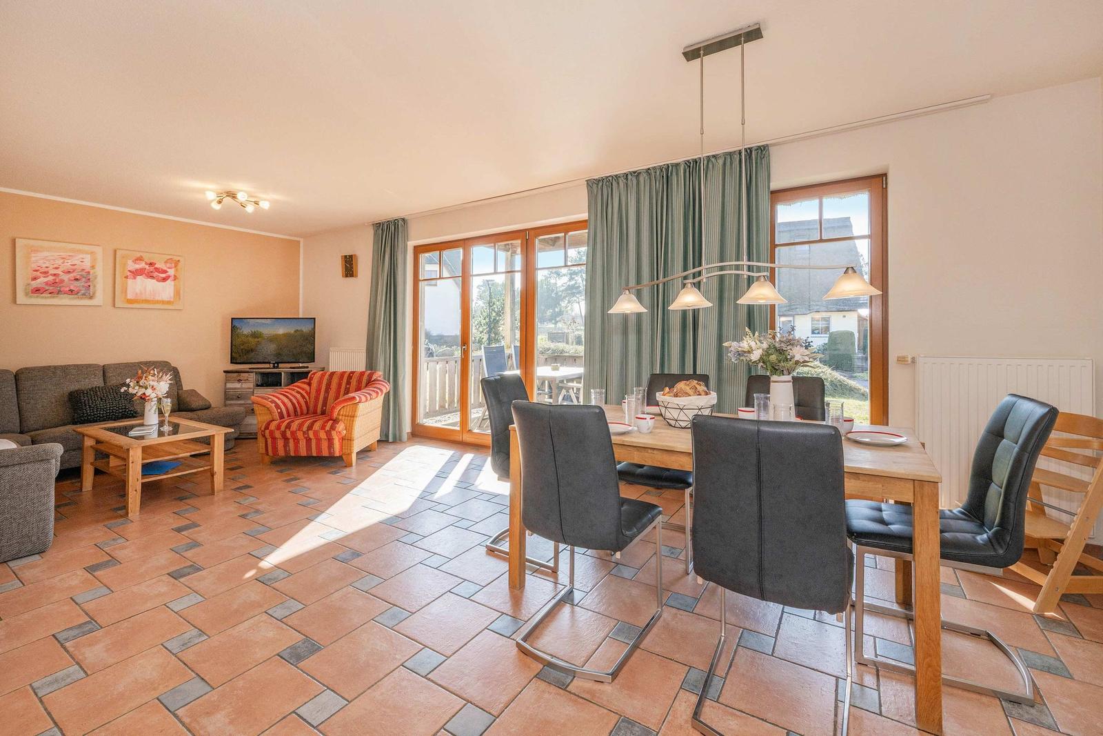Wohn- und Essbereich mit Terrassentür, Esstisch, Sofa und Sessel.
