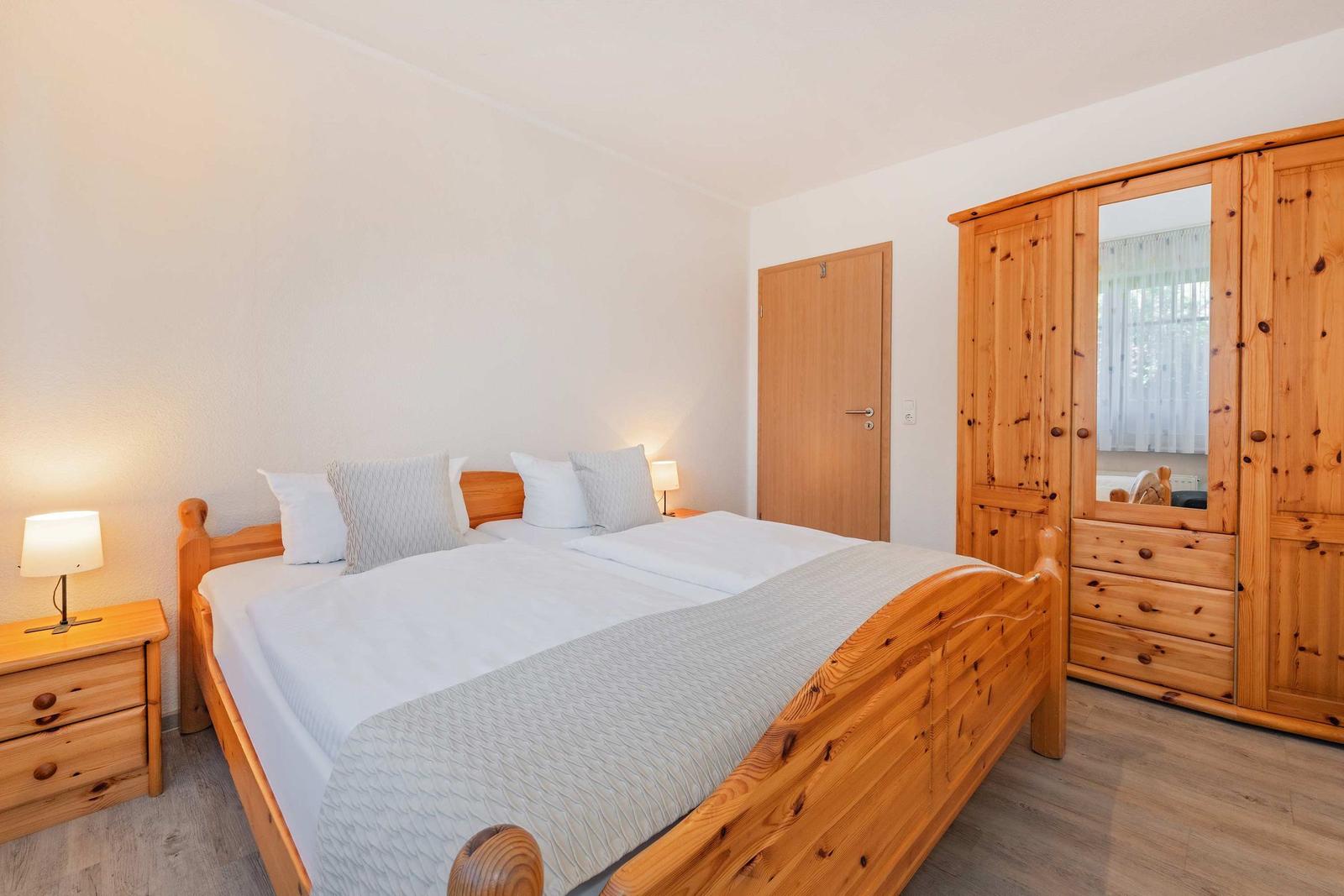 Schlafzimmer mit Holzbett, Nachttisch und Kleiderschrank.
