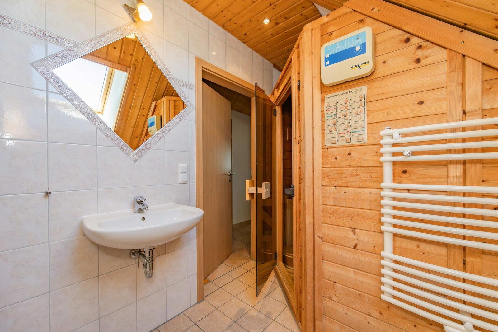Bad mit Waschbecken, Spiegel und integrierter Sauna.