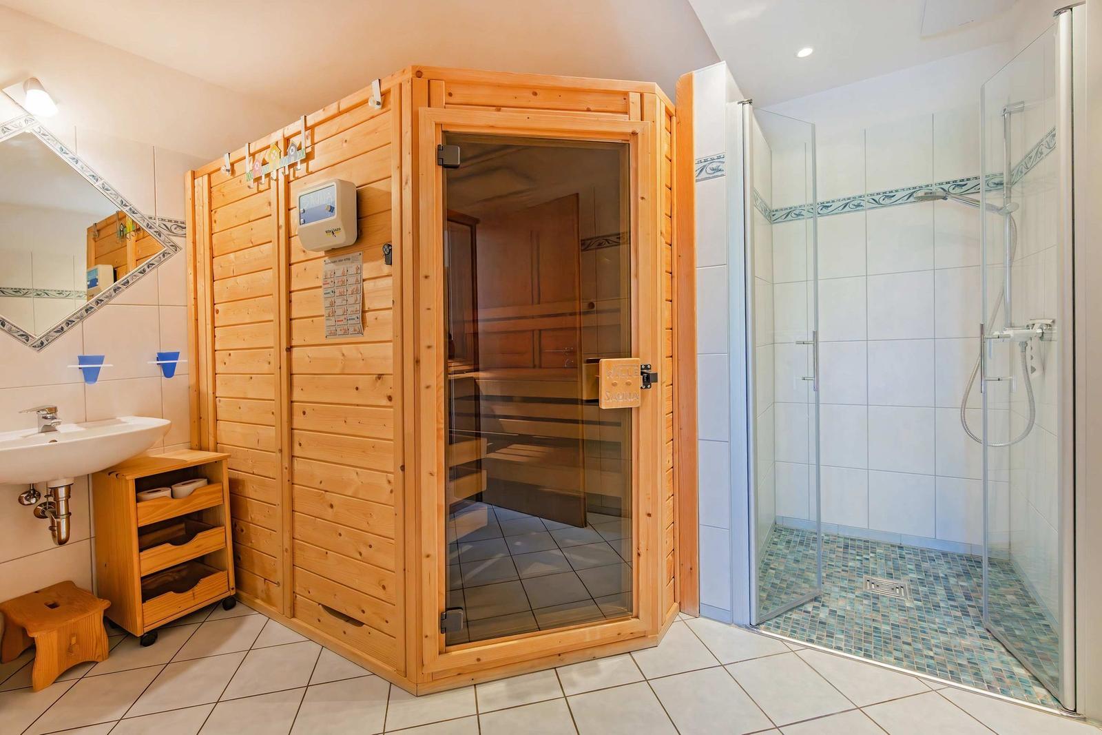Dusche mit Glaswand, Sauna und Waschbecken mit Spiegel