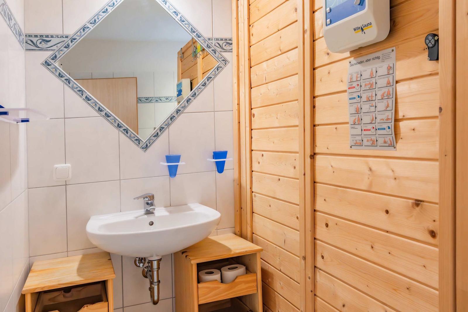 Badezimmer mit Waschbecken, Spiegel und Holzwand