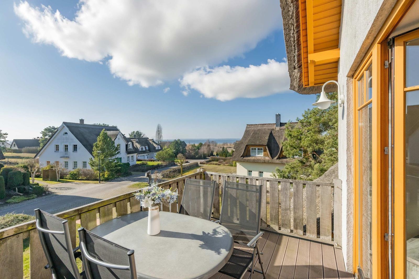 Terrasse mit Tisch und Stühlen. Blick auf traditionelle Häuser und Landschaft.