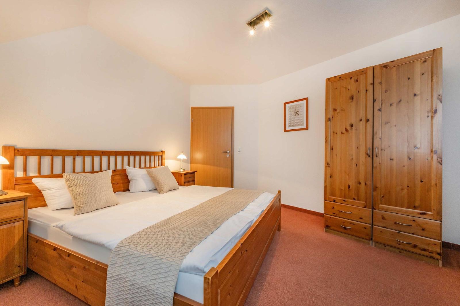 Schlafzimmer mit Holzbett, Kleiderschrank und Nachttisch.