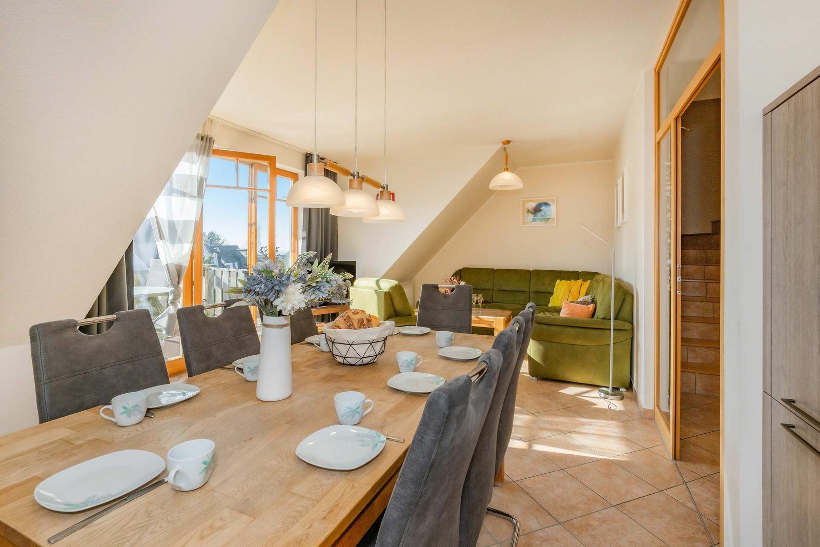Esszimmer mit Tisch, Stühlen und Blick auf Wohnbereich mit Sofa.