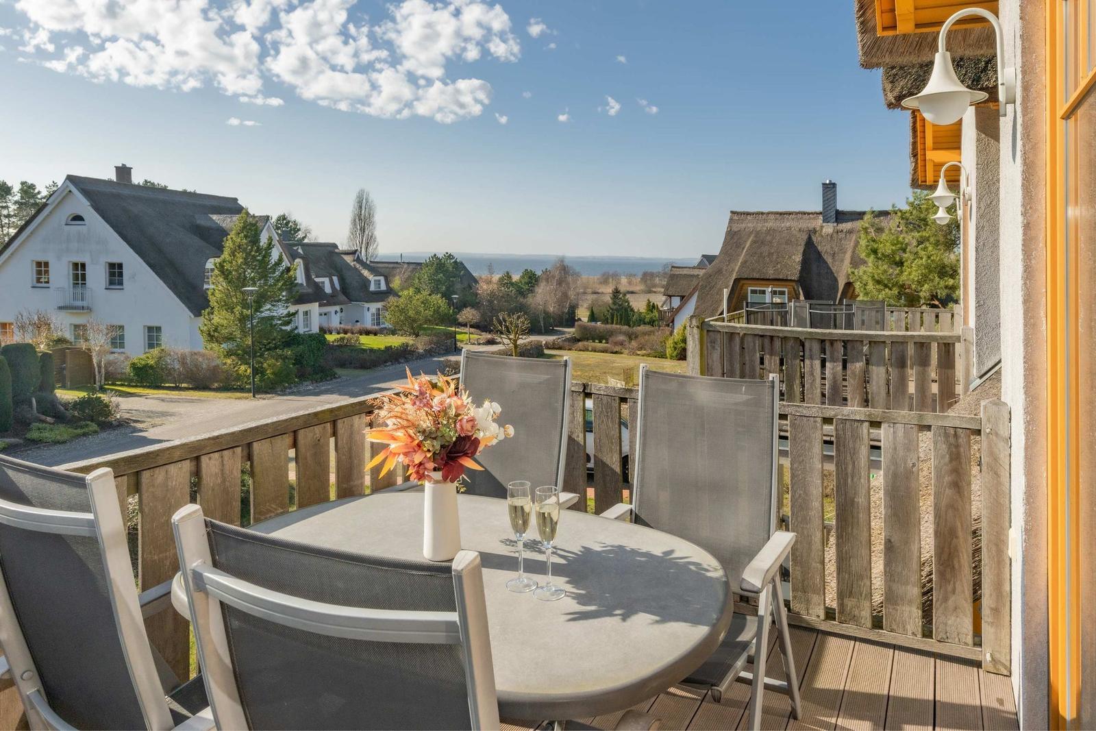 Terrasse mit Tisch und Stühlen, Blick auf Häuser und Meer.