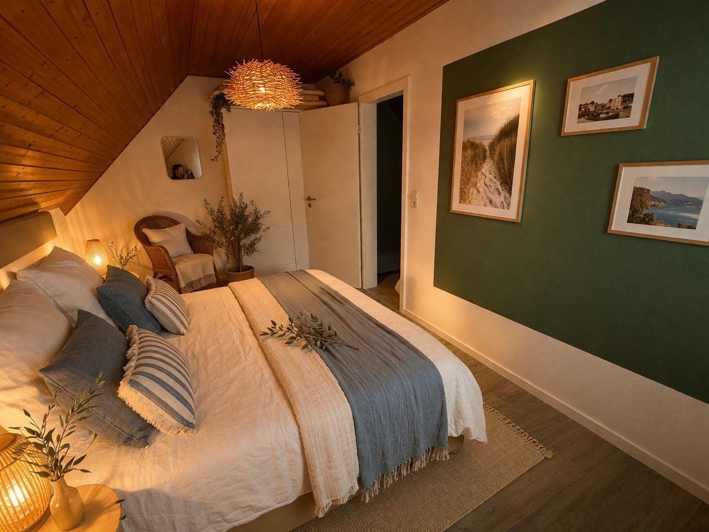 Schlafzimmer mit Dachschrägen, Bett, Wandbildern und Holzboden.