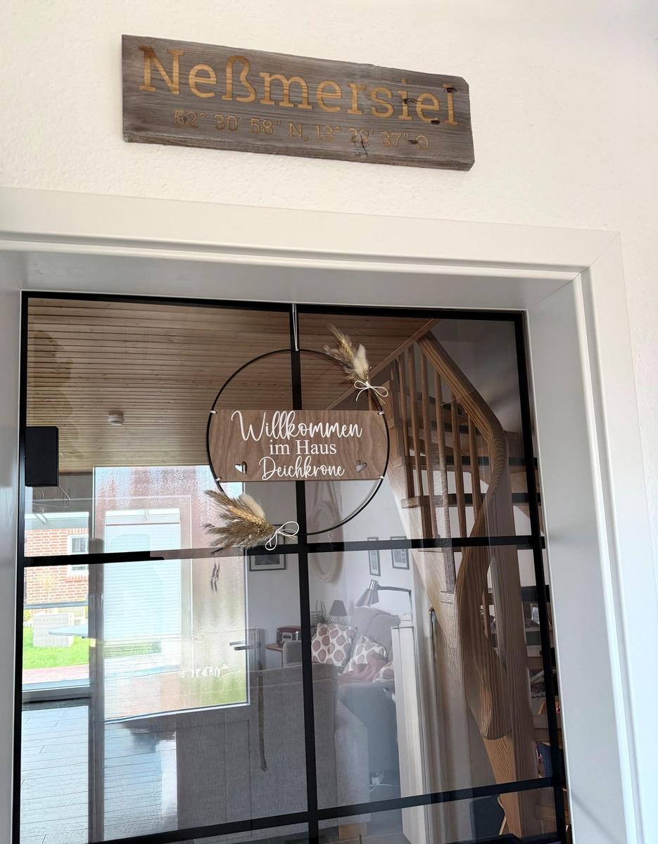 Eingangstür mit Schild Willkommen im Haus Deuchkrone und Koordinaten von Neßmersiel.