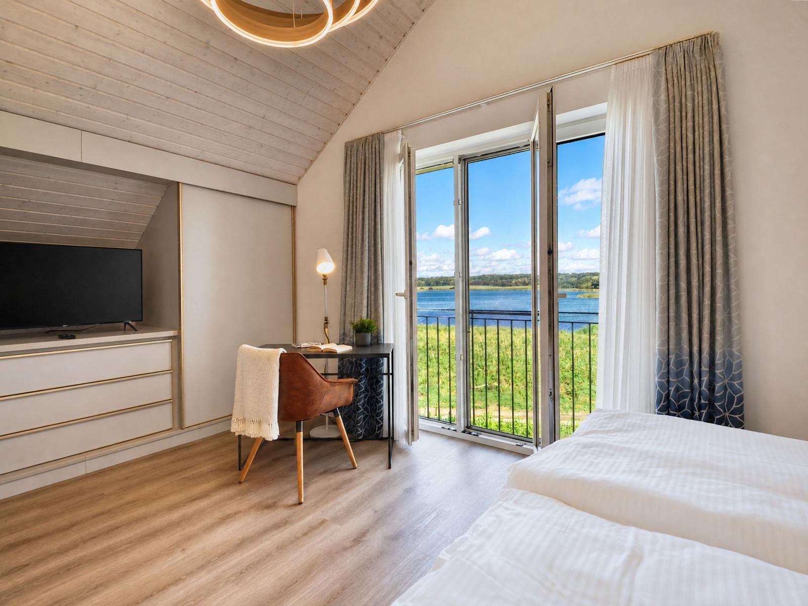 Schlafzimmer mit Blick auf See, Schreibtisch und TV.