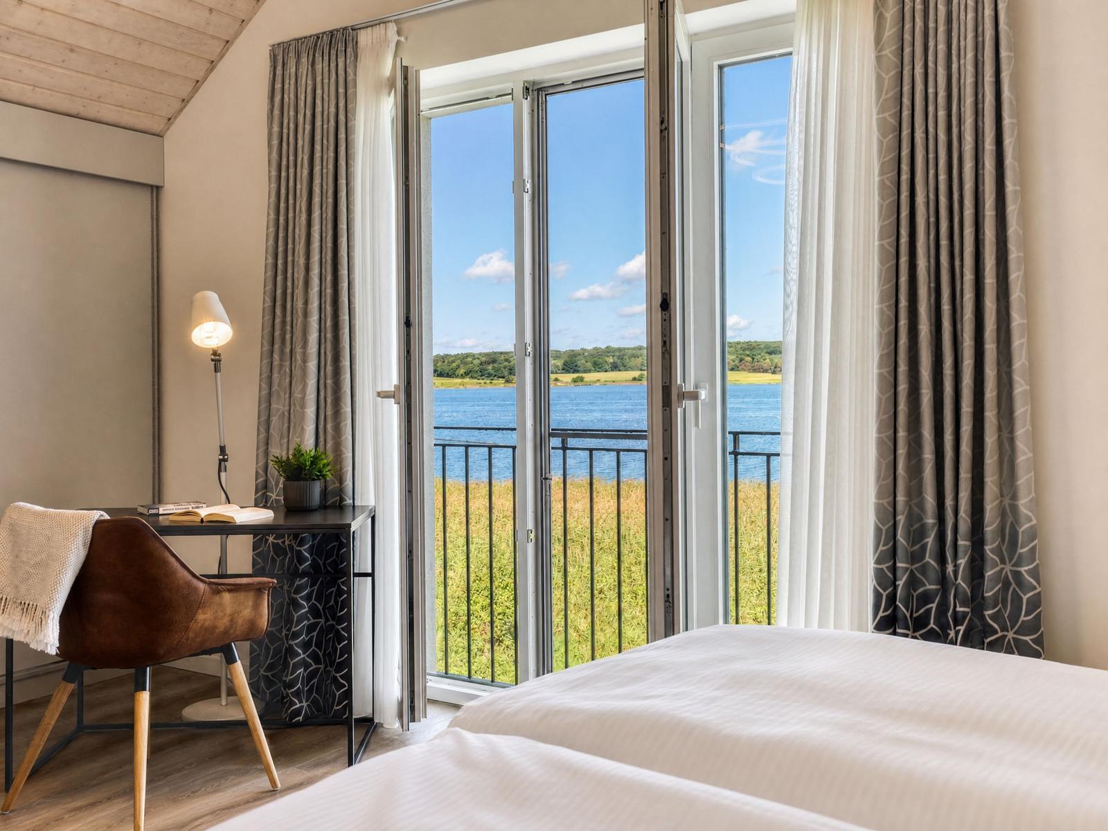 Zimmer mit Blick auf See, Balkon, Schreibtisch und Bett