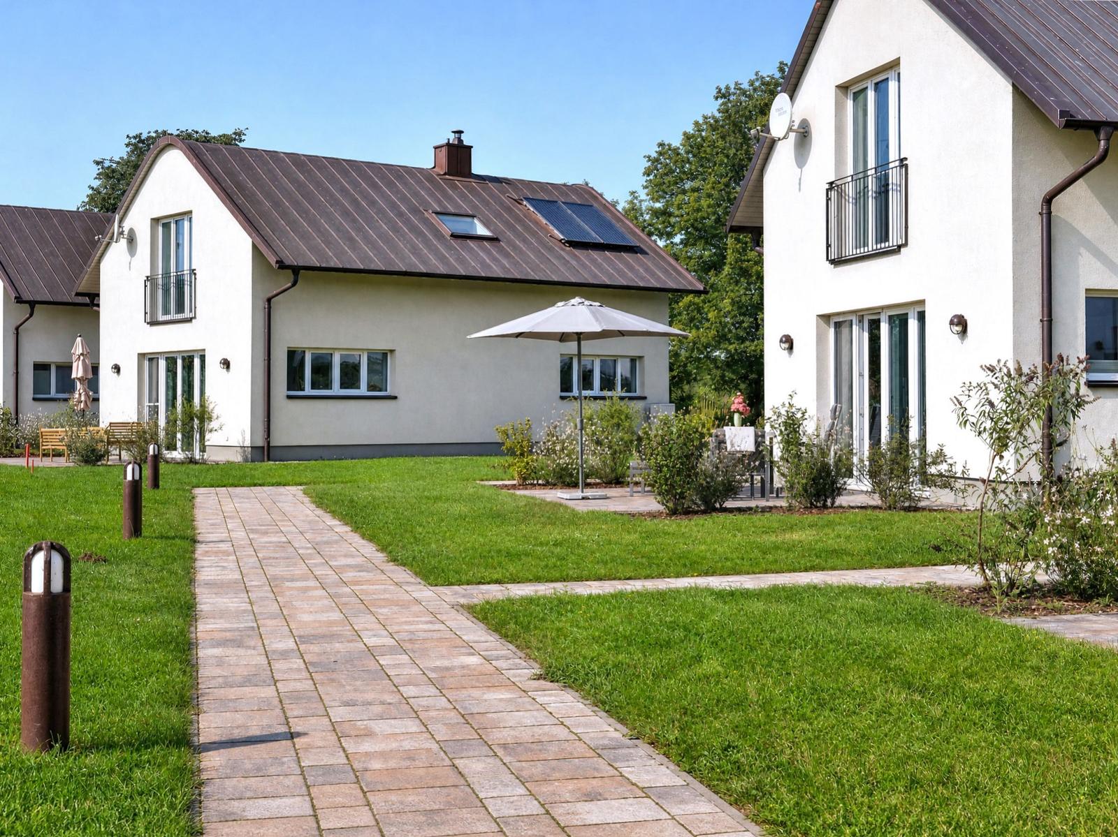 Haus mit Garten, Terrasse und Sonnenschirm. Steinerne Pfade durch das Gras.