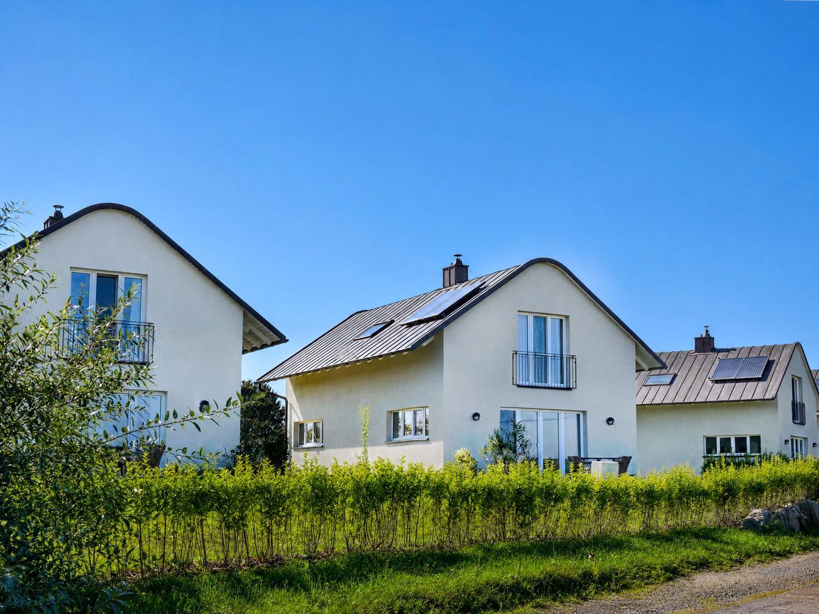 Moderne Häuser mit Solaranlagen und Balkonen unter blauem Himmel.