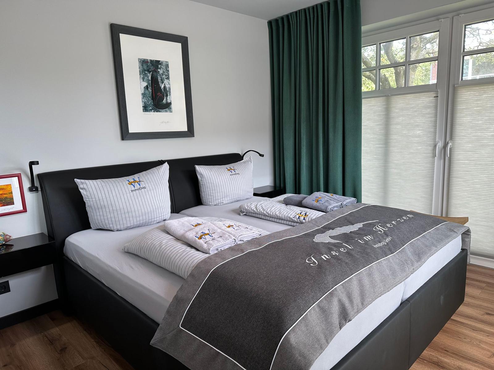 Schlafzimmer mit Doppelbett, grünen Vorhängen und Fenster mit Blick auf Bäume.