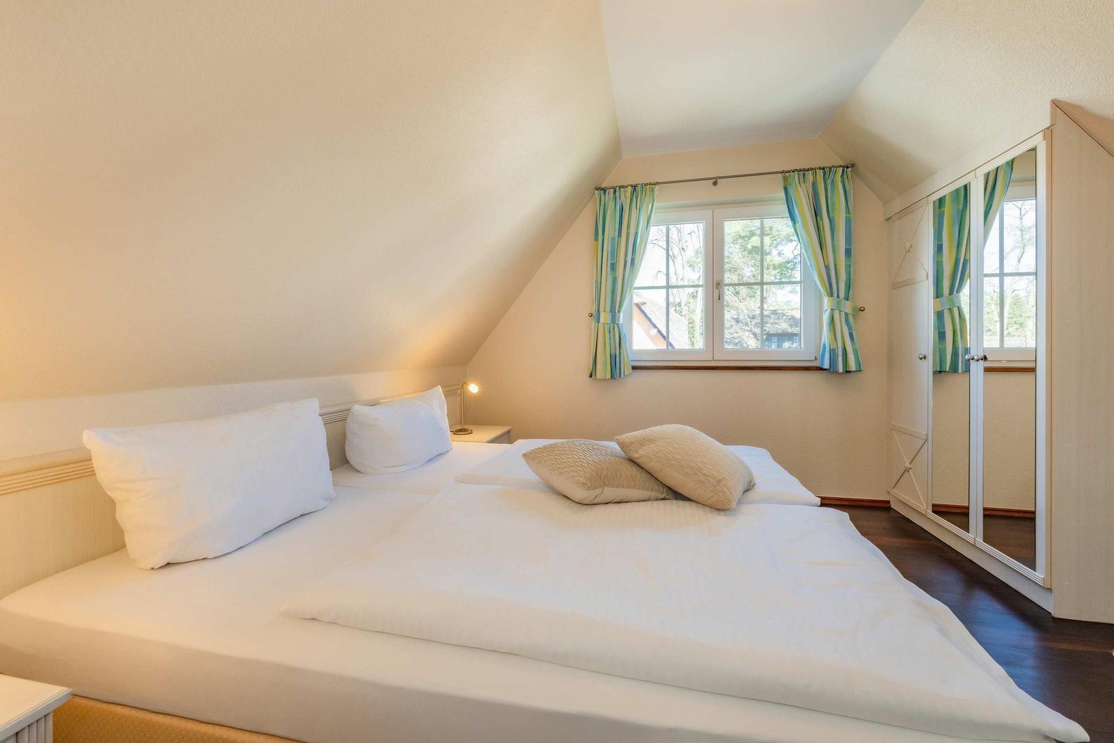 Schlafzimmer mit Dachschrägen, Fenster und Schrank.