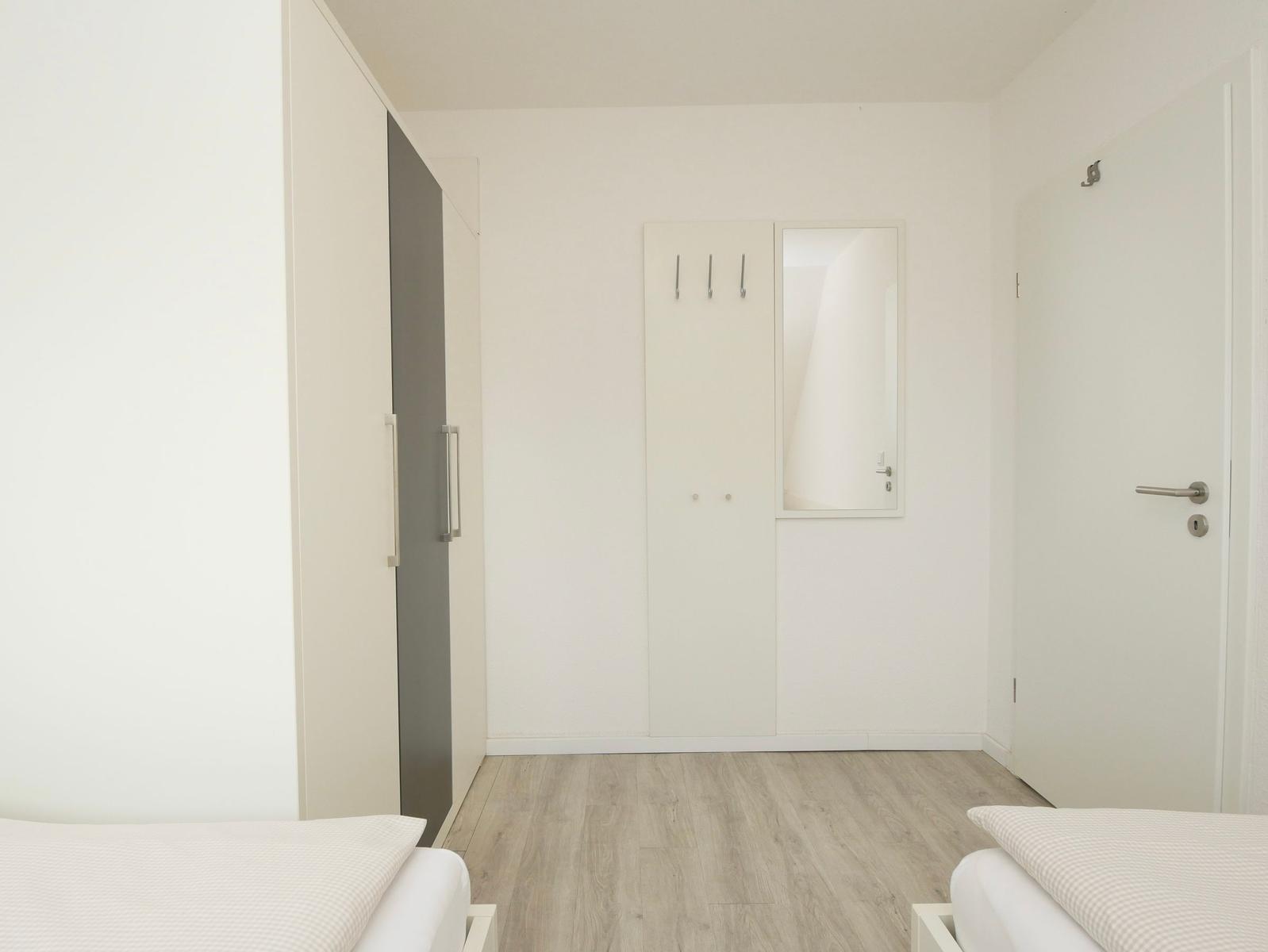 Zimmer mit zwei Betten, Kleiderkabinen und Holzboden