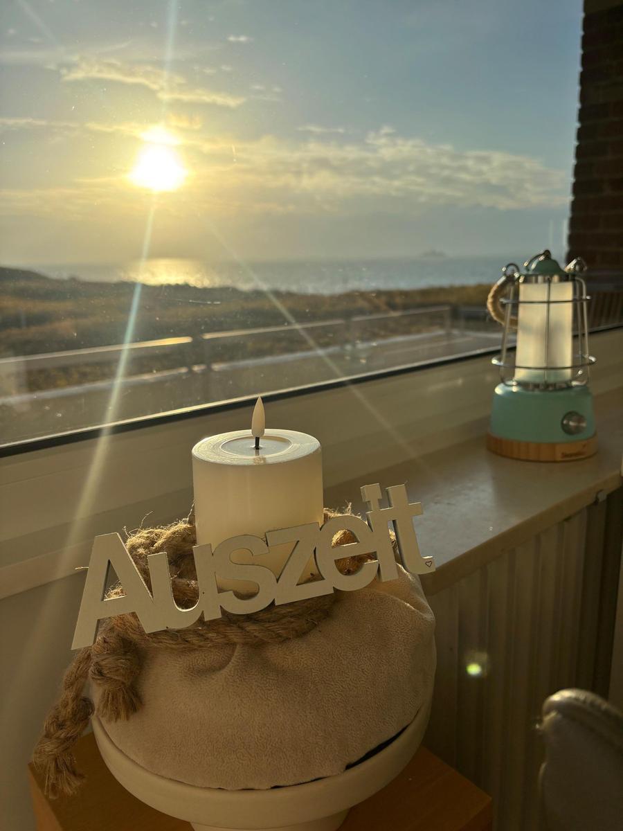 Sonnenaufgang über Meer aus dem Fenster. Kerze und Laterne auf Fensterbank.