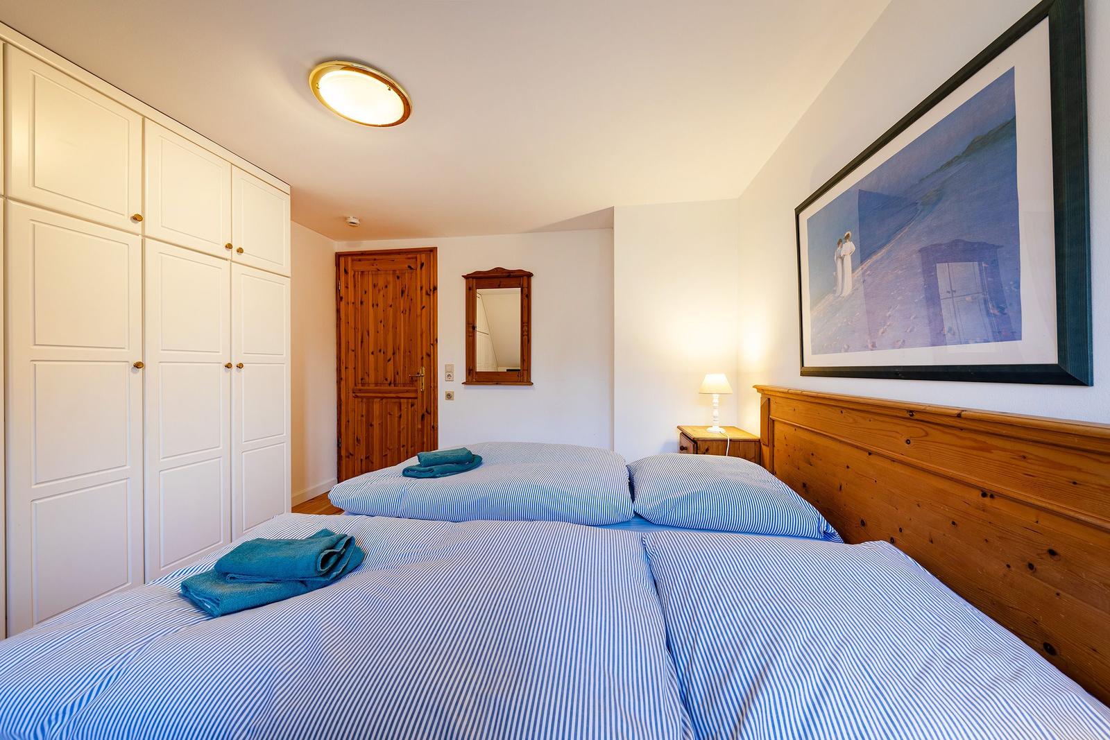 Schlafzimmer mit Doppelbett, Kleiderschrank und Wandbild.