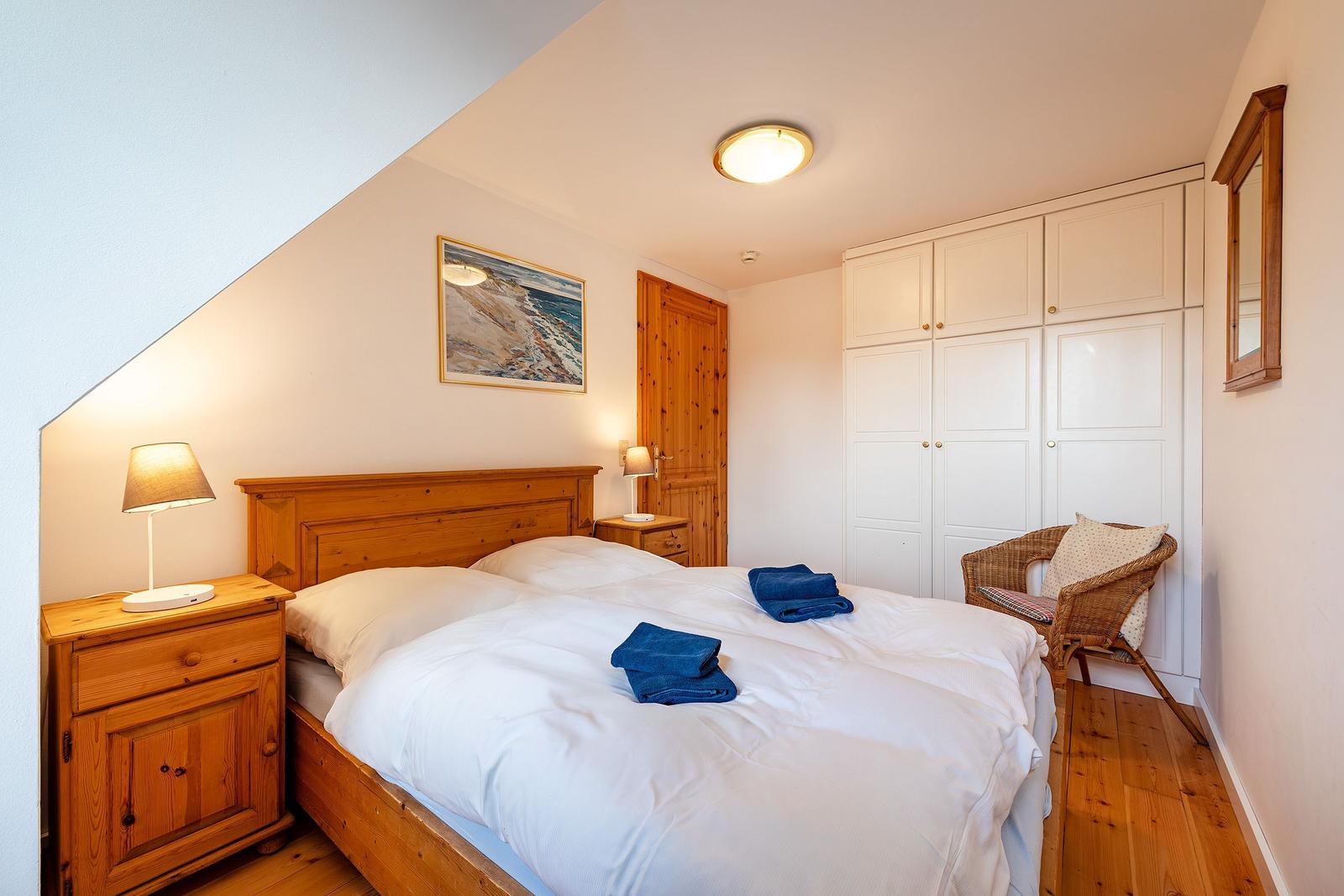 Schlafzimmer mit Doppelbett, Holzmöbeln und Kleiderschrank.
