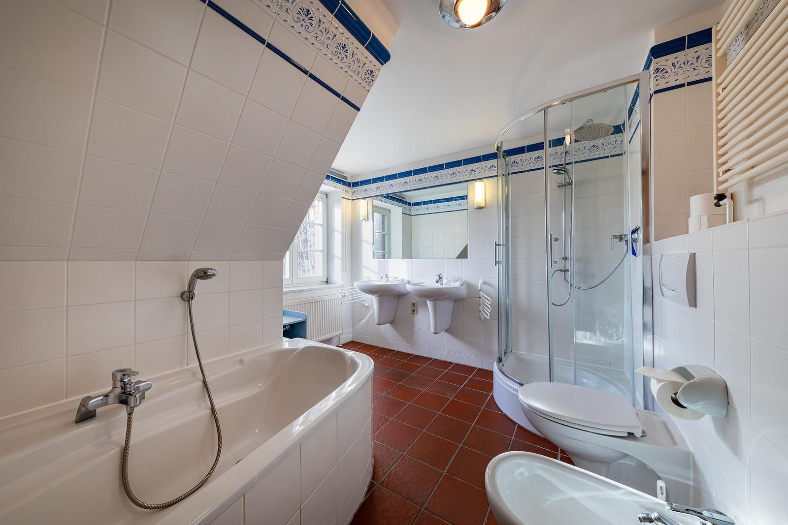 Badezimmer mit Badewanne, Dusche, Toilette und zwei Waschbecken.