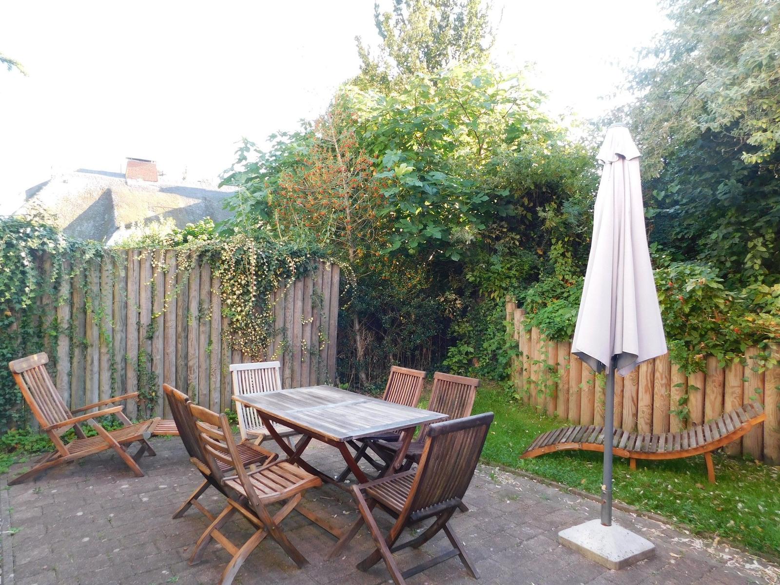 Hinterhof mit Holztisch, Stühlen und geschlossener Sonnenschutz