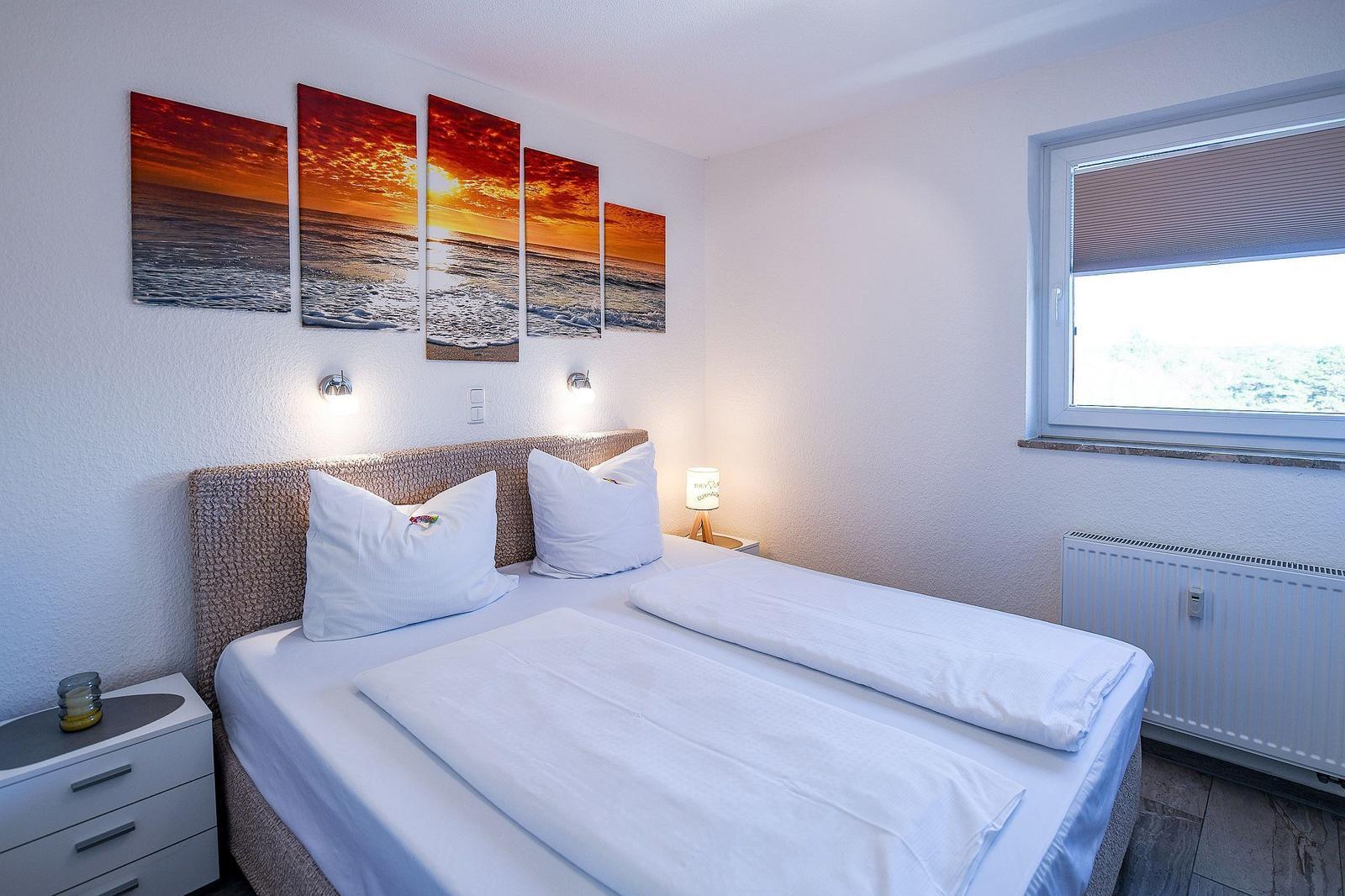 Schlafzimmer mit Bett, Fenster und Wandbildern