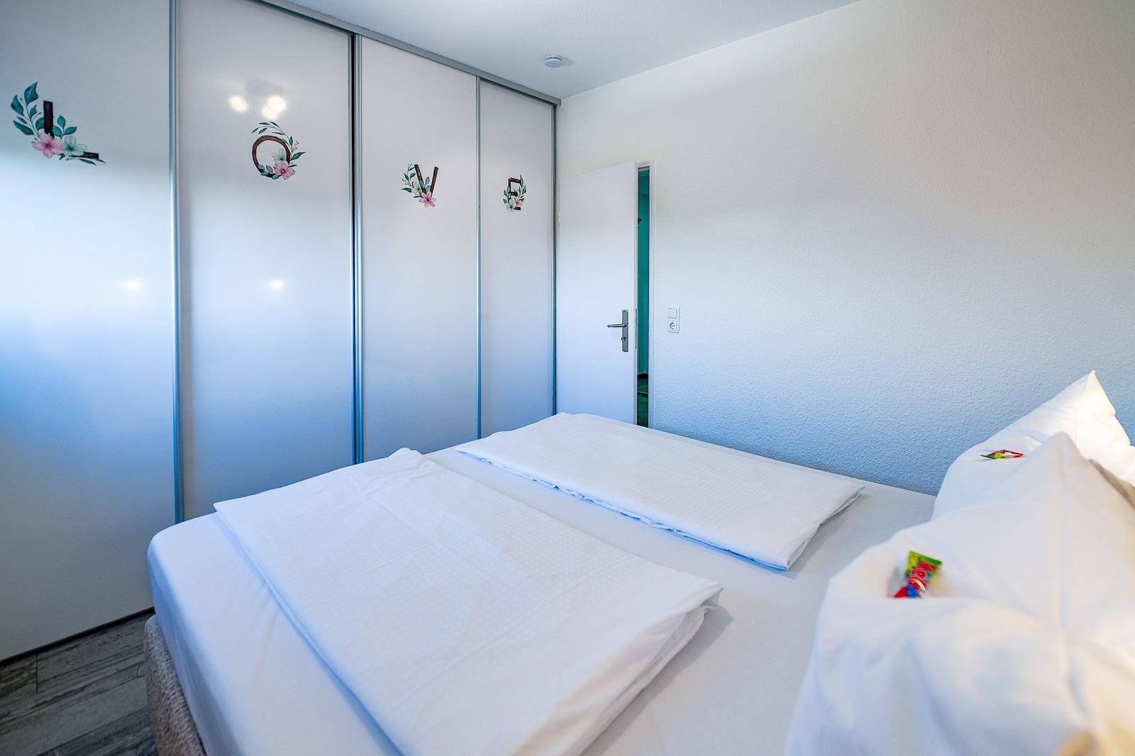 Schlafzimmer mit Doppelbett und Schwebetüren mit Dekoration.