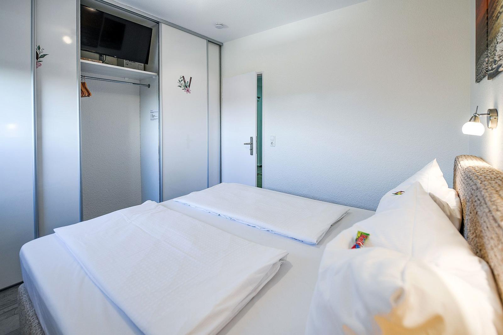 Schlafzimmer mit Bett, Kleiderschrank und Fernseher.