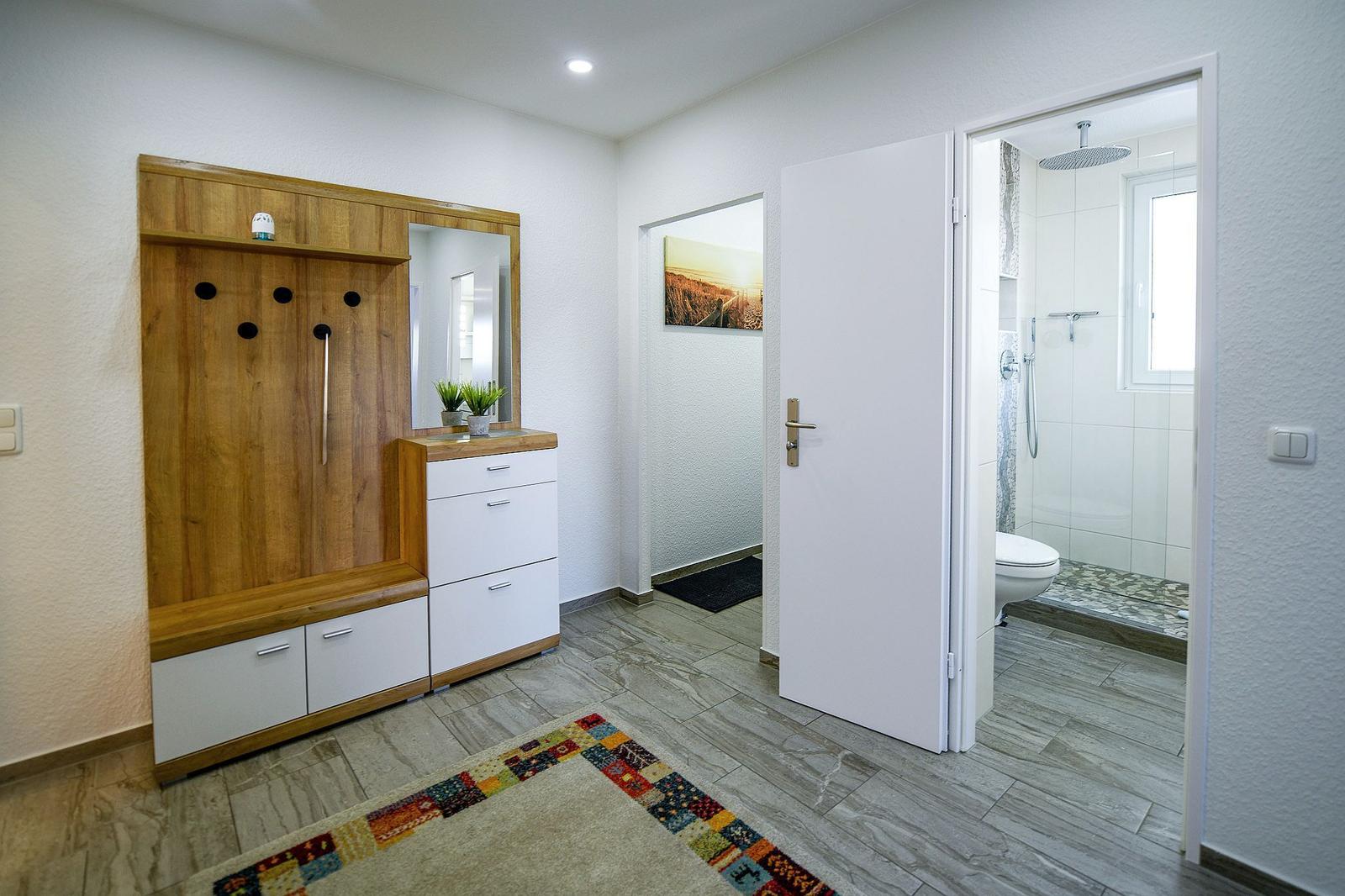 Eingangsbereich mit Garderobe, Spiegel und Flur zur Toilette und Dusche.