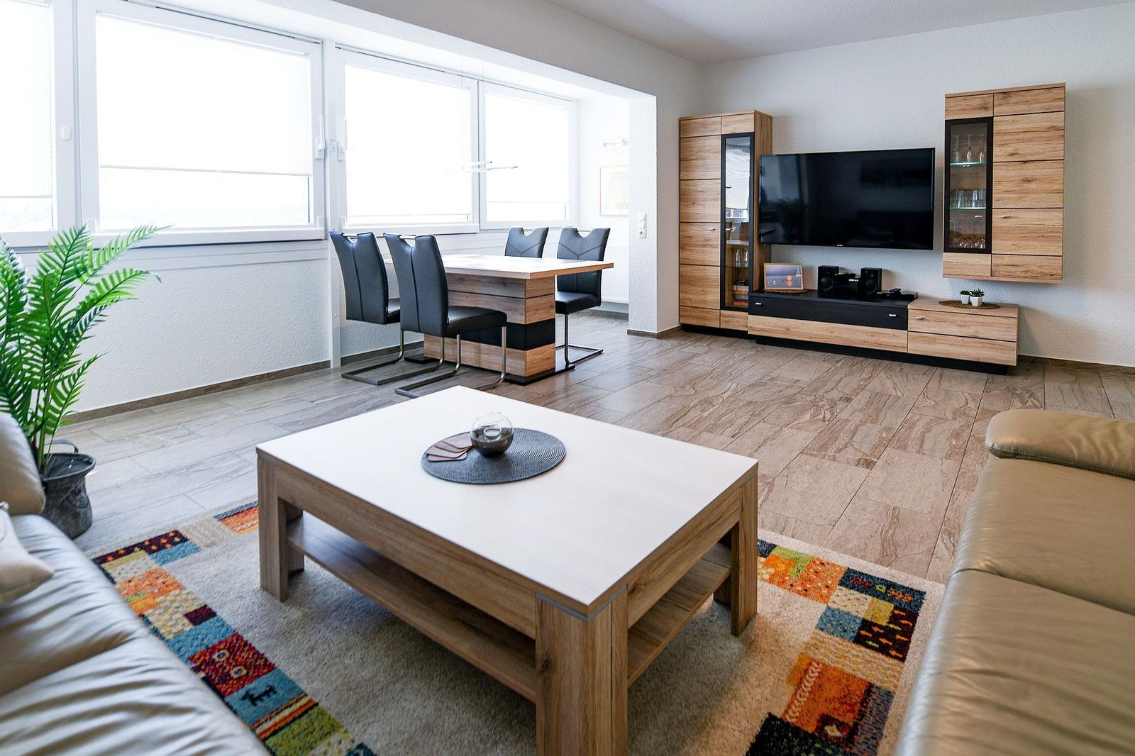 Wohn- und Essbereich mit Holzmöbeln, TV und großem Fenster.